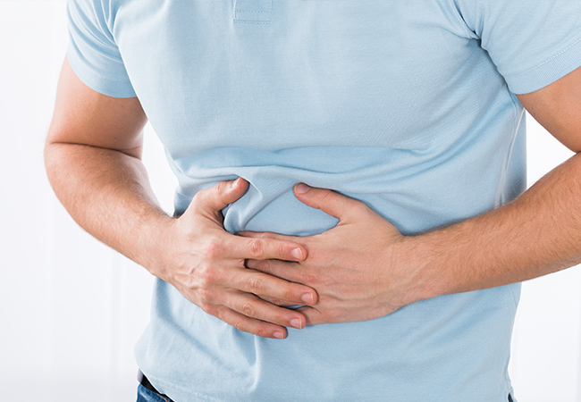 胃のあたりを両手でおさえる男性